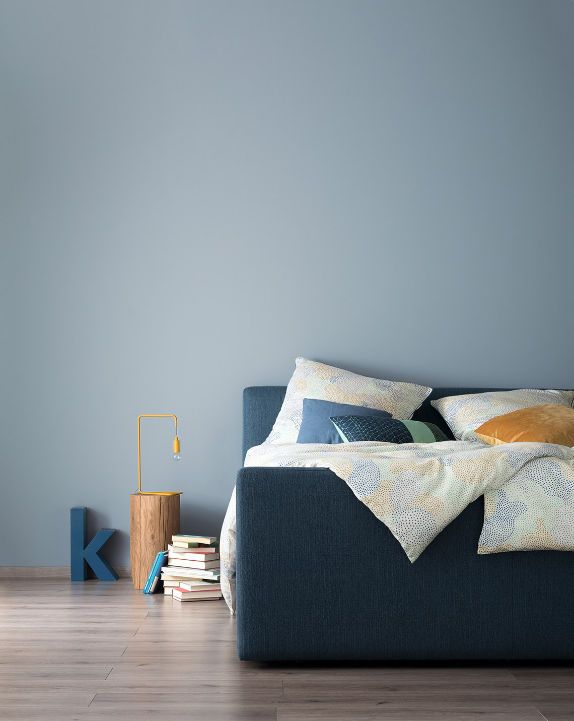 Schlafzimmer mit Bett und Wand in Designfarbe Entspanntes Nordischblau